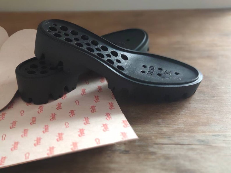 Puede incluir: Dos plantillas de zapatos negras con un patr&oacute;n de panal y el texto "0514 38" en la parte inferior.