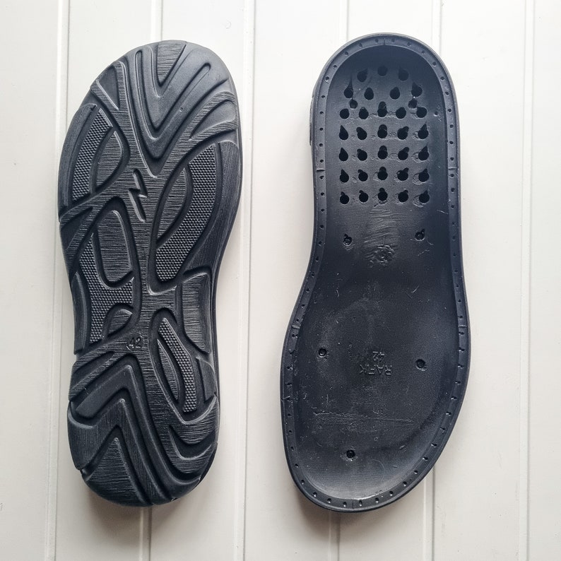 May include: A pair of black shoe insoles. One insole has a textured surface and the other has a pattern of small holes.