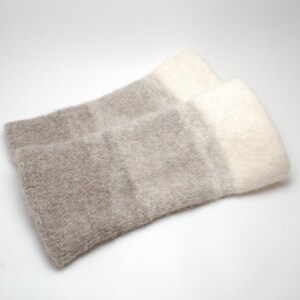May include: A pair of soft, fuzzy arm warmers with a gradient of beige and white.