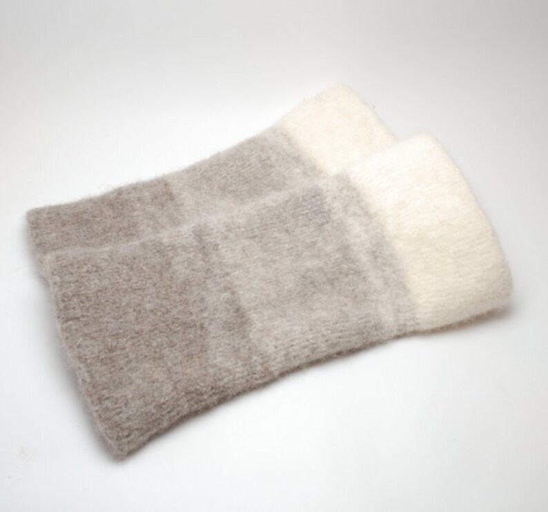 May include: A pair of soft, fuzzy arm warmers with a gradient of beige and white.