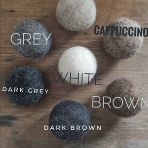 Pode incluir: Conjunto de bolas de feltro em v&aacute;rias cores, incluindo bege, cinza, branco, cappuccino, cinza escuro, marrom e marrom escuro.