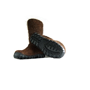 May include: A pair of brown wool slippers with black rubber soles. The slippers are folded over at the top and the soles are visible.