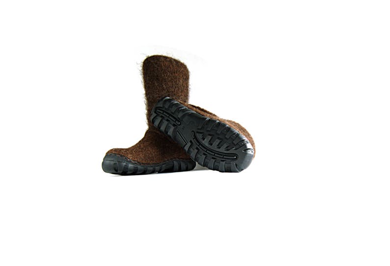 May include: A pair of brown wool slippers with black rubber soles. The slippers are folded over at the top and the soles are visible.