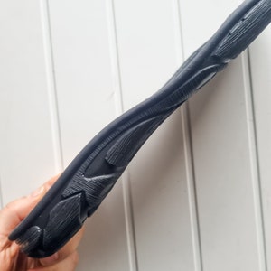 May include: Close-up of the black rubber sole of a shoe with a detailed, textured design.