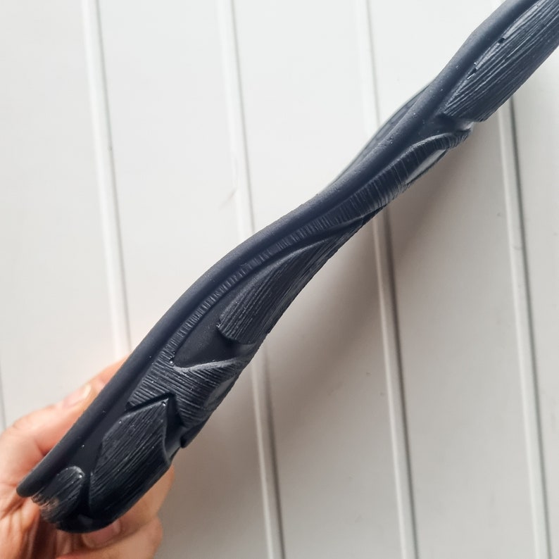 May include: Close-up of the black rubber sole of a shoe with a detailed, textured design.