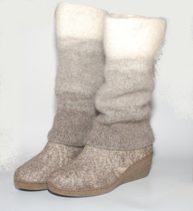 May include: A pair of gray and white knit boots with a wedge heel. The boots are made of a soft, fuzzy material and have a slouchy look.