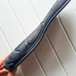 May include: Close-up of a black rubber strap with a textured surface and a Nike swoosh logo.