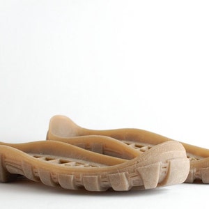 May include: A pair of brown rubber shoe soles with a textured tread pattern.