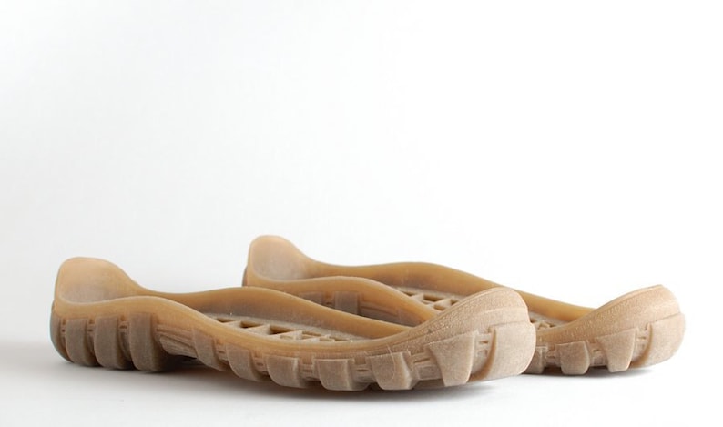 May include: A pair of brown rubber shoe soles with a textured tread pattern.