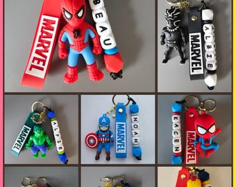 May include: A collection of Marvel-themed keychains featuring various superhero figures, including Spider-Man, Black Panther, Hulk, Captain America, Deadpool, Wolverine, and Iron Man, paired with personalized name beads and red, blue, or black straps.