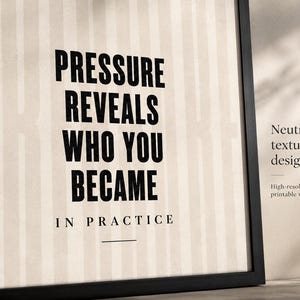 May include: A framed print with the text "PRESSURE REVEALS WHO YOU BECAME IN PRACTICE" in bold black letters. The background has vertical stripes. The frame is black. Additional text reads "Neutral textured design" and "High-resolution printable wall art."