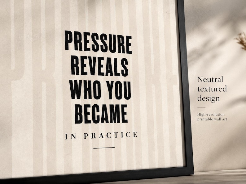 May include: A framed print with the text "PRESSURE REVEALS WHO YOU BECAME IN PRACTICE" in bold black letters. The background has vertical stripes. The frame is black. Additional text reads "Neutral textured design" and "High-resolution printable wall art."