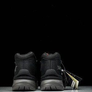 May include: Two black hiking boots with grey soles, seen from behind. The boots feature a textured upper and a small logo. A tag is attached to one boot.