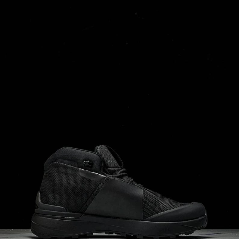 May include: Black high-top hiking boot. The boot has a mesh and smooth material construction, a thick sole, and a padded collar. Designed for outdoor use, it offers ankle support. The boot's design is modern and functional.