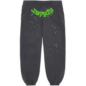 May include: Dark gray sweatpants with the word "reggas" in bright green, accented with white, green, and black star graphics. The sweatpants have an elastic waistband and cuffs, and pockets on the sides.