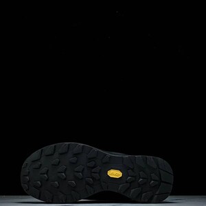 May include: Black hiking shoe sole with a textured pattern and a yellow Vibram logo. The sole is designed for grip and durability, suitable for outdoor activities. The shoe is likely for trail running or hiking.