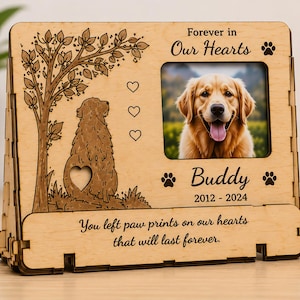 Puede incluir: Marco de fotos conmemorativo de mascotas de madera con una foto de un golden retriever. El marco tiene un diseño de árbol y silueta de perro, huellas de patas y el texto "Forever in Our Hearts" y "Buddy 2012-2024". La parte inferior dice "You left paw prints on our hearts that will last forever."