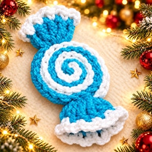Peut inclure: Un ornement en forme de bonbon crocheté présentant un motif en spirale central en fil bleu vif et blanc. Les extrémités du bonbon sont évasées avec une bordure blanche texturée, créant un effet d'emballage distinct avec une laine épaisse.