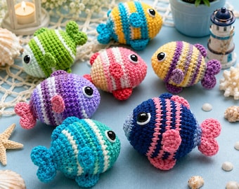 May include: A collection of six small, round, crocheted fish toys, each featuring horizontal stripes in various color combinations including blue, yellow, green, pink, and purple, with black plastic eyes and small crocheted fins and tails.