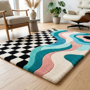 Pode incluir: Um tapete retangular com um design dividido. Uma metade apresenta um padrão de xadrez preto e branco, enquanto a outra metade exibe faixas de cores onduladas e fluidas em tons de azul-petróleo, azul-claro, rosa suave e branco creme.