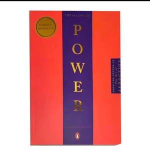 May include: A book titled "The 48 Laws of Power" with a red cover and a purple vertical band. The word "POWER" is in gold letters. A gold "National Bestseller" sticker is on the upper left.