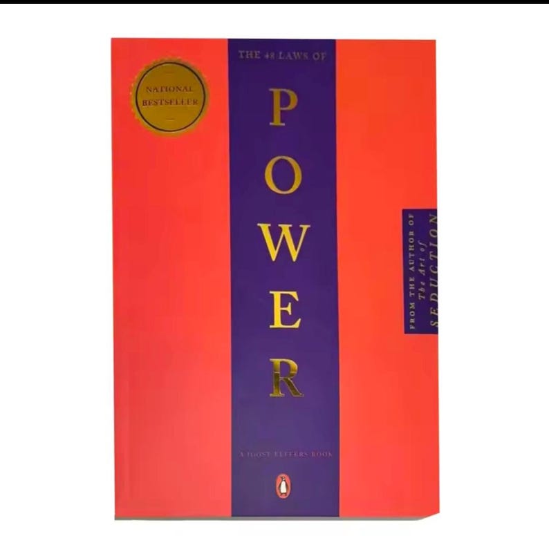 May include: A book titled "The 48 Laws of Power" with a red cover and a purple vertical band. The word "POWER" is in gold letters. A gold "National Bestseller" sticker is on the upper left.