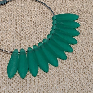 May include: A silver hoop earring with a cluster of green teardrop-shaped beads hanging from the bottom.