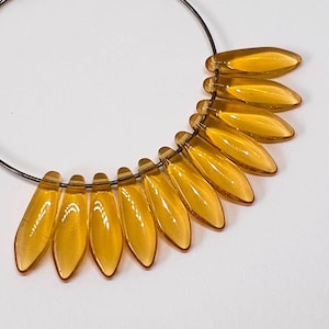 May include: A silver hoop earring with a cluster of amber-coloured glass teardrop beads hanging from the bottom.