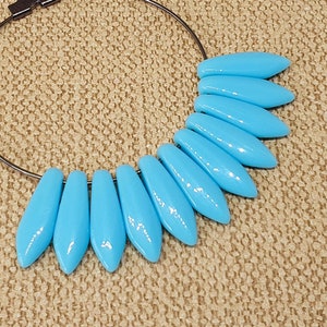 May include: A hoop earring with a silver-toned metal hoop and a cluster of light blue teardrop-shaped beads.