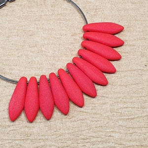 May include: A silver hoop earring with a row of bright red teardrop-shaped beads.