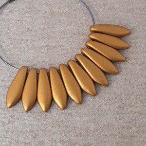 May include: A gold hoop earring with a cluster of gold teardrop-shaped beads hanging from the bottom.