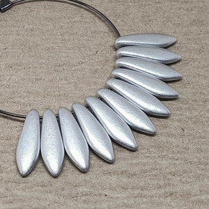 May include: Silver hoop earrings with a silver leaf design. The earrings are made of metal and have a simple, elegant design.