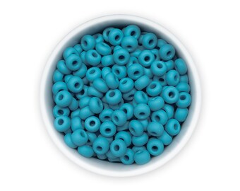 Può includere: Una ciotola bianca piena di perline rotonde di colore blu turchese. Le perline sono piccole e hanno una finitura liscia e opaca.