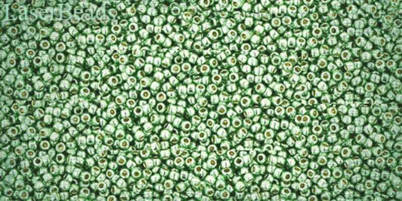 May include: A close-up image of a large quantity of small, round, green glass beads. The beads have a metallic sheen and are arranged in a random pattern.