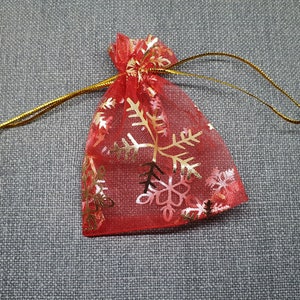 May include: Red mesh gift bag with gold snowflake pattern and gold drawstring.