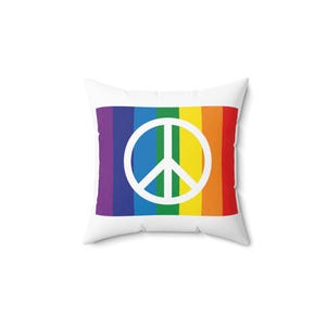 Può includere: Cuscino quadrato bianco con un design a righe arcobaleno e un simbolo di pace bianco. Le strisce arcobaleno includono viola, blu, verde, giallo, arancione e rosso. Articolo decorativo.