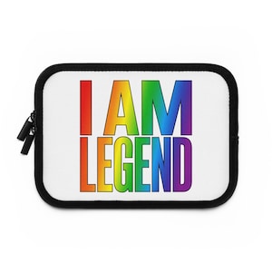 Può includere: Una custodia bianca per laptop con cerniera e finiture nere. Le parole "I AM LEGEND" sono stampate a colori arcobaleno sul davanti, con il testo in grassetto e senza grazie.