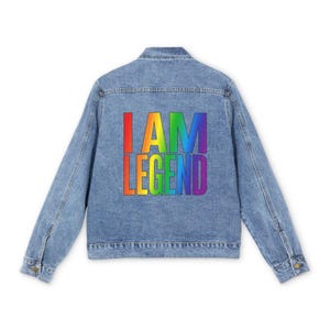 Può includere: Giacca di jeans blu chiaro con la scritta "I AM LEGEND" nei colori dell'arcobaleno sul retro. La giacca ha un design classico con chiusure a bottoni, tasche e maniche lunghe.
