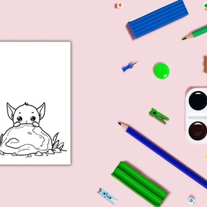Può includere: Illustrazione in bianco e nero di un personaggio dei cartoni animati che sbuca da una roccia, su sfondo bianco. L'immagine è circondata da materiali artistici, tra cui matite blu e verdi, vernice e plastilina, su una superficie rosa.