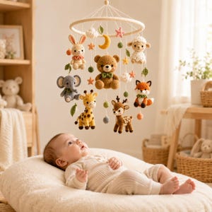 Könnte beinhalten: Ein Häkel-Babymobile mit einem zentralen braunen Bären, umgeben von einem Hasen, Elefanten, einer Giraffe, einem Reh, einem Fuchs und einem Schaf, ergänzt durch kleine gehäkelte Sterne, einen Mond, Wolken und Blätter an einem Holzring.