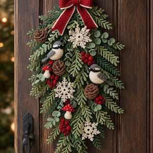 Può includere: Una decorazione da parete all'uncinetto con una disposizione rigogliosa di fogliame verde, due piccoli uccelli, bacche rosse, pigne marroni, fiocchi di neve bianchi e due funghi rossi e bianchi, sormontata da un grande fiocco rosso all'uncinetto.
