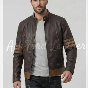 May include: A dark brown leather jacket featuring a stand-up collar, a full-length front zip, and two vertical zipped chest pockets. The sleeves are accented with three horizontal brown stripes, and the hem is finished with a brown leather band.