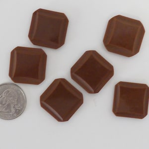 May include: Six brown, square-shaped buttons with beveled edges. The buttons are approximately the size of a US quarter.