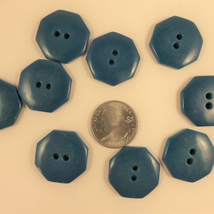 May include: Eight teal blue octagonal buttons with two holes each. The buttons are arranged in a circle around a US quarter.