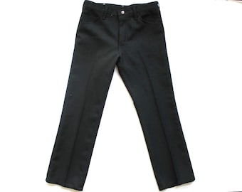 May include: A pair of solid black trousers featuring a classic five-pocket design, a front button closure, and a metal zipper fly. The pants have a straight-leg cut with a visible crease running down the center of each leg, providing a structured look.