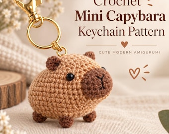 May include: A tan crochet capybara keychain with dark brown accents, black bead eyes, and a gold-toned metal lobster clasp. The text reads: Crochet Mini Capybara Keychain Pattern, CUTE MODERN AMIGURUMI. The design features a small, rounded body.