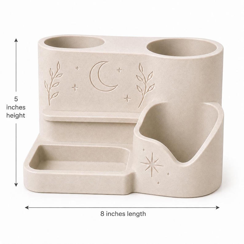 May include: A beige desk organizer with two cylindrical pen holders, a rectangular tray, and a curved compartment. The front features engraved moon, star, and leaf motifs. It measures 5 inches in height and 8 inches in length as indicated by arrows.