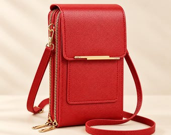 May include: A bright red crossbody bag with a textured finish, featuring a front flap with a horizontal gold-tone metal bar accent, two zippered compartments, and a matching thin adjustable shoulder strap attached with gold-tone metal clips.