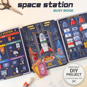 Pode incluir: Um livro de atividades de estação espacial com três painéis apresentando uma plataforma de lançamento, estação de suprimentos e peças de foguete. Inclui ilustrações coloridas de equipamentos espaciais, itens de missão e moeda. Tesoura visível.
