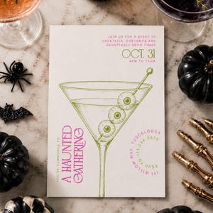 May include: A rectangular invitation card featuring a green line-art illustration of a martini glass with three eyeballs on a pick. Text reads: JOIN US FOR A NIGHT OF COCKTAILS, COSTUMES AND HAUNTINGLY GOOD TIMES, OCT. 31, 8PM TO 12AM, A HAUNTED GATHERING.